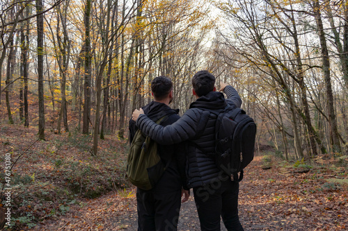 Two boys are walking on the forest. One of them showing far away to others. Friendship and brotherhood concept photo. Hiking, sport and active lifestyle concept photo. Fresh air at outdoor.