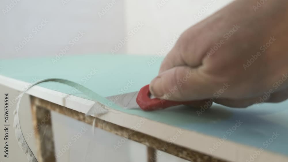 Builder cuts off the edge of drywall with knife. Preparation for the installation of plasterboard panels. 4K video, close-up selective focus. Simple and affordable renovation of premises and offices Builder cuts off the edge of drywall with knife. Preparation for the installation of plasterboard panels. 4K video, close-up selective focus. Simple and affordable renovation of premises and offices