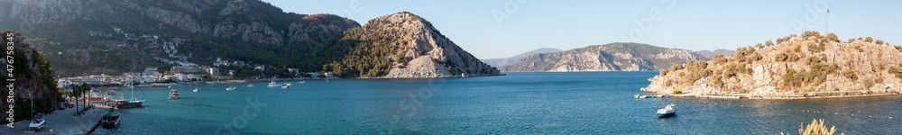 Sea bay surrounded by mountains and rocks in small touristic village Turunc. Landscape with moored pleasure yacht. Panoramic view