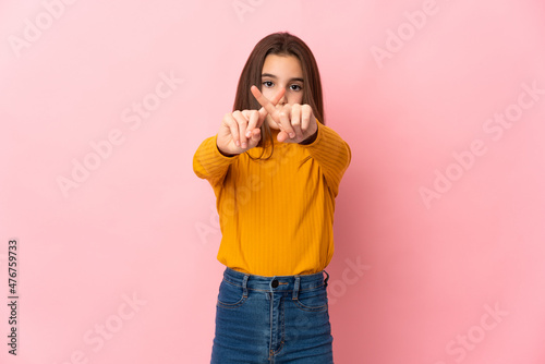 Little girl isolated on pink background making stop gesture with her hand to stop an act
