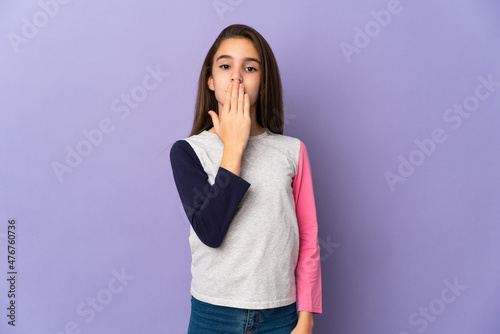 Little girl isolated on purple background covering mouth with hand