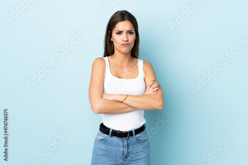 Young caucasian woman isolated on blue background with unhappy expression