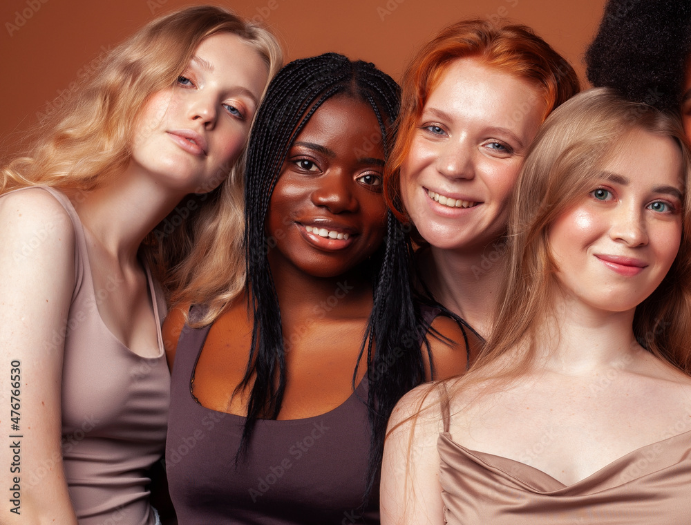 Obraz premium young pretty african and caucasian women posing cheerful together on brown background, lifestyle diverse nationality people concept
