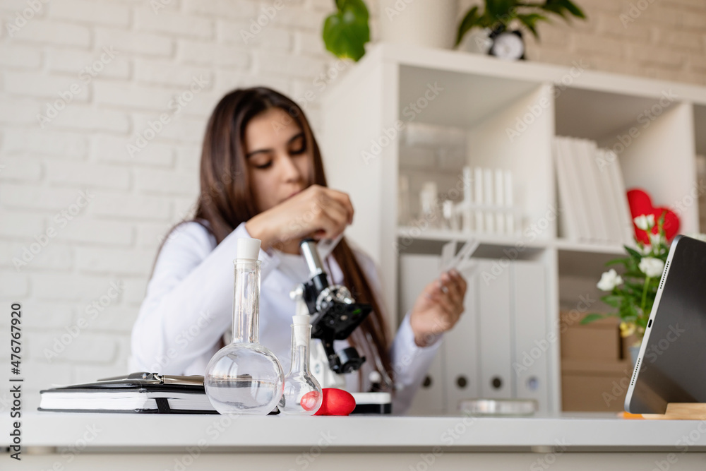 Young doctor or scientist woman using microscope on the background Young doctor or scientist woman using microscope on the background