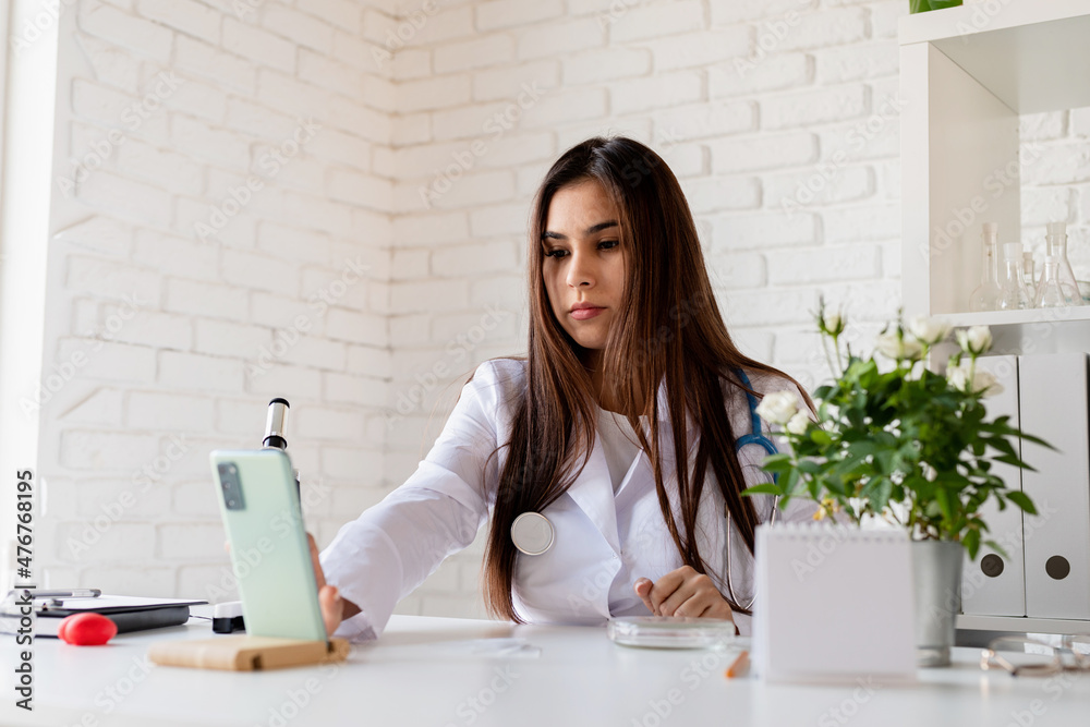 Young doctor or scientist woman using microscope, having online call showing samples, teaching online Young doctor or scientist woman using microscope, having online call showing samples, teaching online