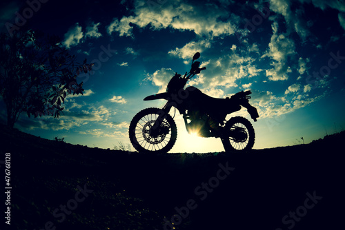 Silhouette of a motocross motorcycle parked on a mountain.