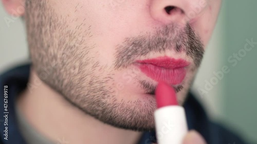Transgender Man Putting Red Lipstick on His Lips Closeup photo