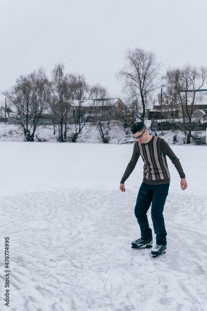a guy in a sweater and glasses is skating on a frozen lake