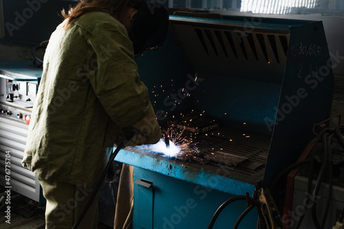 Brunette welder working with welding torch in factory