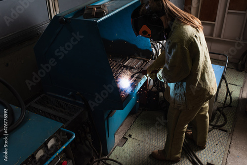 High angle view of welder in uniform working with torch near machine in factory