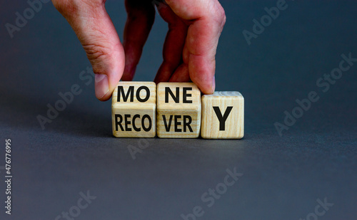 Money recovery symbol. Businessman turns wooden cubes and changes the word money to recovery. Beautiful grey table, grey background, copy space. Business and money recovery concept.