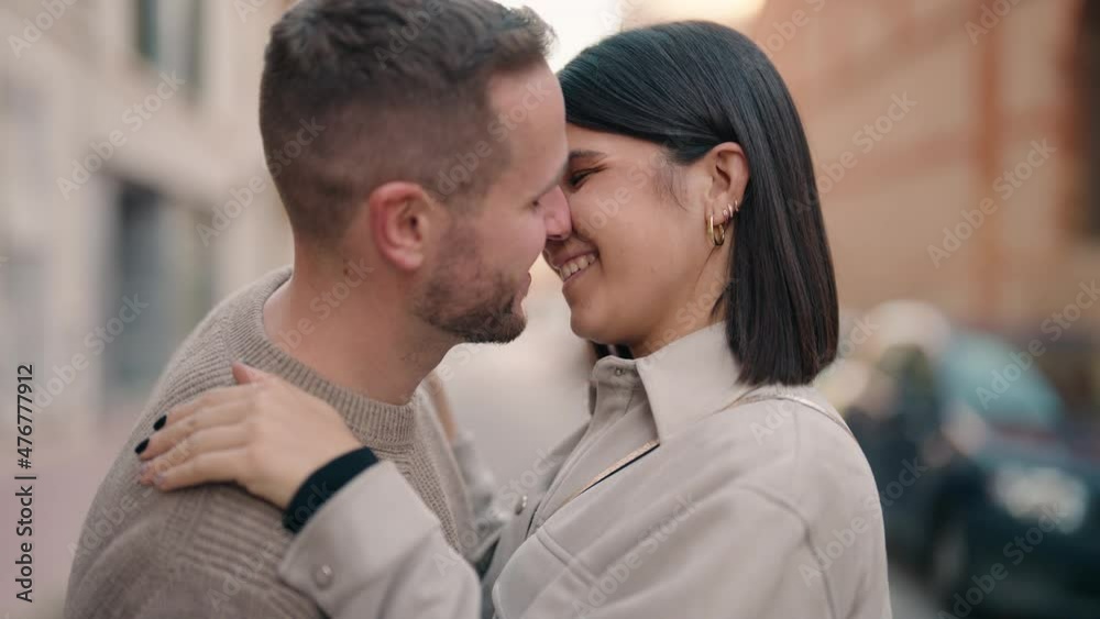 Young couple kissing and hugging each other standing at street