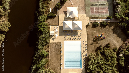 Swimming pool, tennis courts, deck chairs and umbrellas of a tourist village in Sardinia