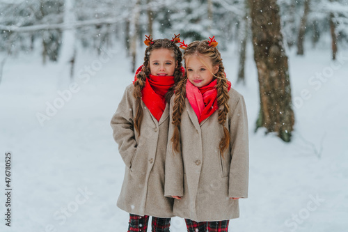 Two sisters i with deer horns stand in a snowy forest. High quality photo