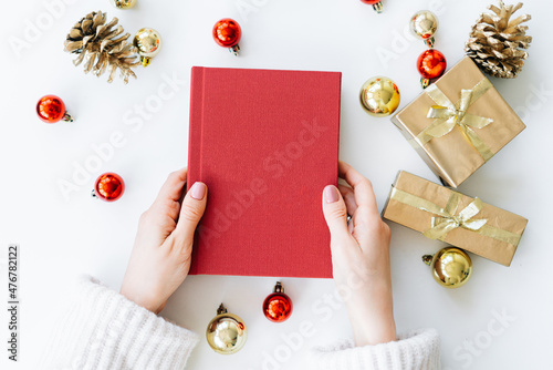a red book in the hands of a young girl against the background of gifts and Christmas toys. the concept of Christmas