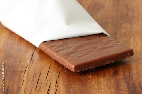 Milk chocolate bar with coconut filling on a wooden background. Milk chocolate. 