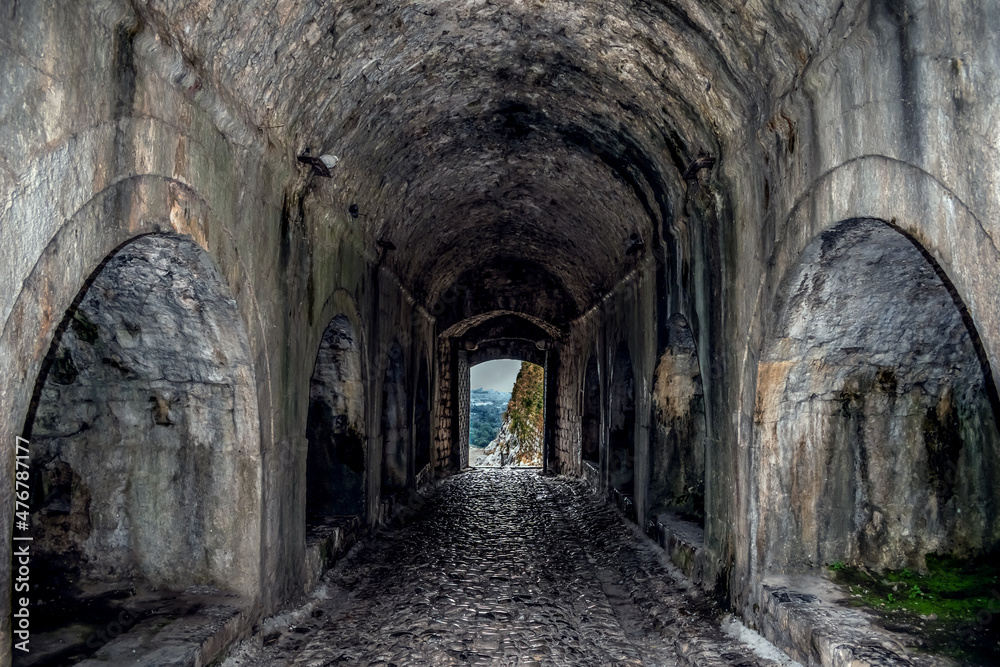 Arched entrance to Rozafa Castle in Shkodra, Albania. Old stone tunnel with a gate at the end - inside view