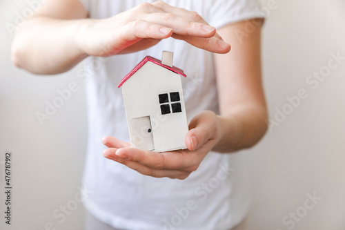 Woman hand holding toy model house isolated on white background. Real estate mortgage property insurance dream home concept. Offer of purchase rental house, family life, business real estate