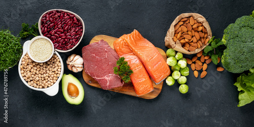 Photography Set of green vegetables, nuts, beans, microgreen with beef meat and salmon fish on dark background top view