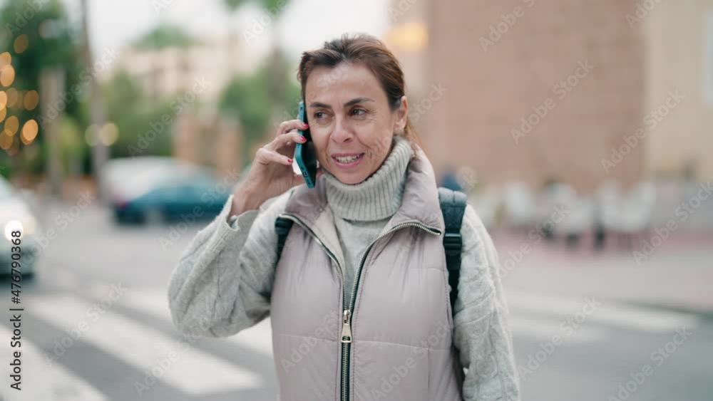 Middle age woman smiling confident talking on the smartphone at street