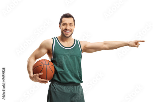Cheerful male basketball player holding a ball and pointing to the side