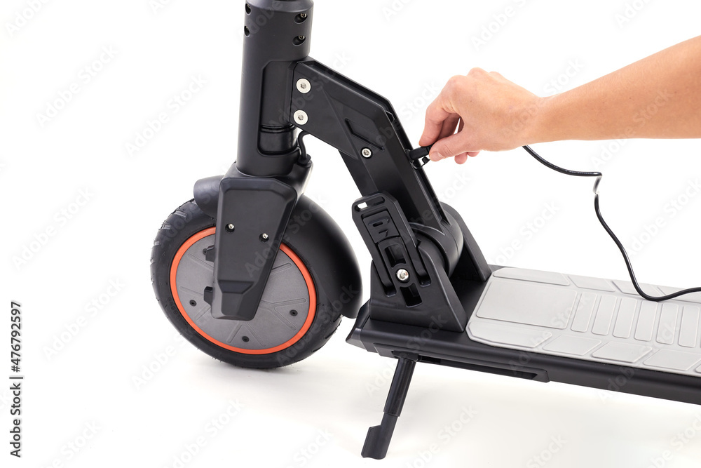 Hand connects the cable to e-scooter. Close up. Battery charging process on a white background. Hand connects the cable to e-scooter. Close up. Battery charging process on a white background.