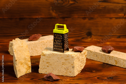 a small grater on a stone on a wooden background