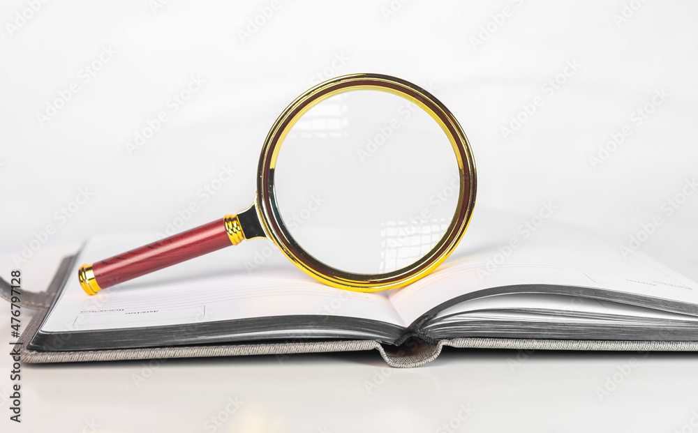 Magnifying glass over open paper art book with pages. Concept of academic research. Magnifying glass over open paper art book with pages. Concept of academic research.