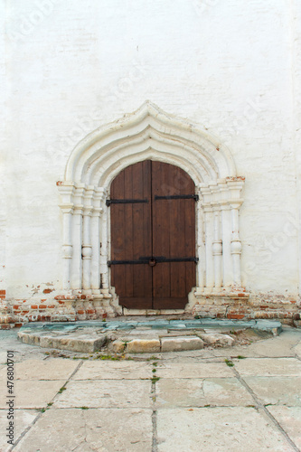 Closed antique double-leaf door in the portal type doorway. The door is locked. The door to the stone cathedral. The arch of the entrance is visible  the area in front of the door. Daylight.