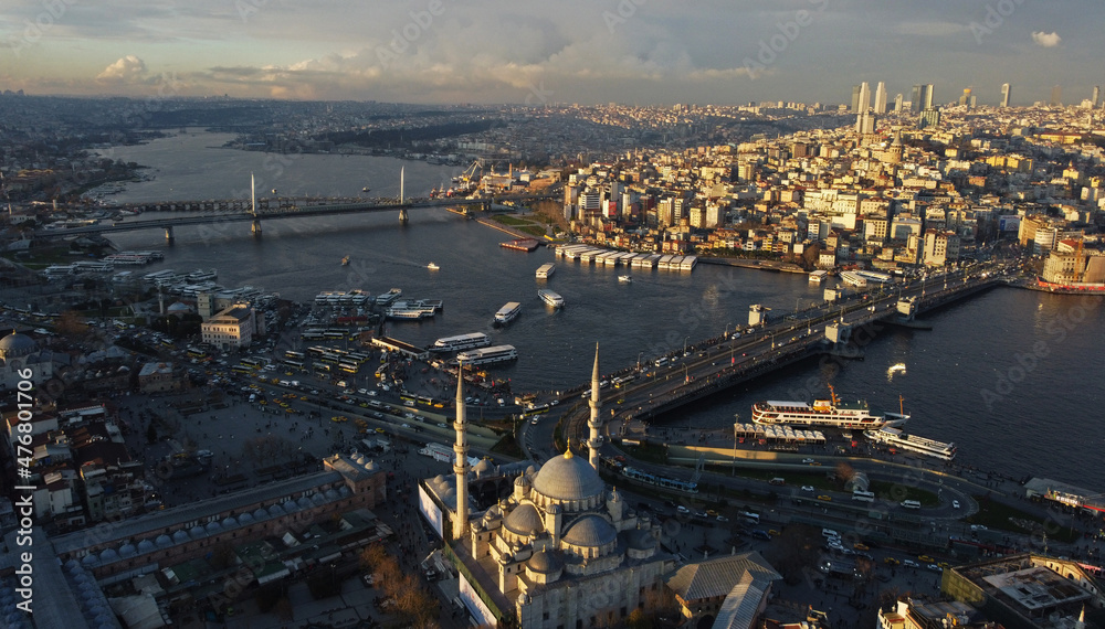 Aerial view of Galata bridge, right, and Halic metro bridge located in the Golden horn waterway, city of Istanbul, Turkey, during sunset. The New Mosque is seen in the bottom.