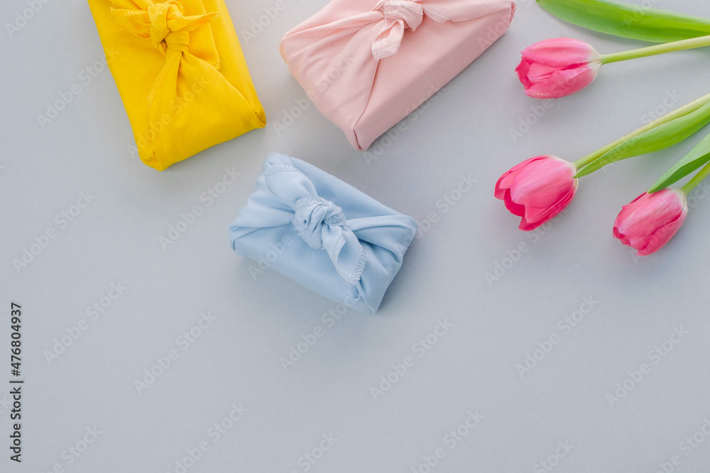 Beautiful composition of tulip and gift on grey background. Valentine's Day, Easter, 8th march, Happy Women's Day, Mother's Day. Flat lay, top view. Beautiful composition of tulip and gift on grey background. Valentine's Day, Easter, 8th march, Happy Women's Day, Mother's Day. Flat lay, top view.