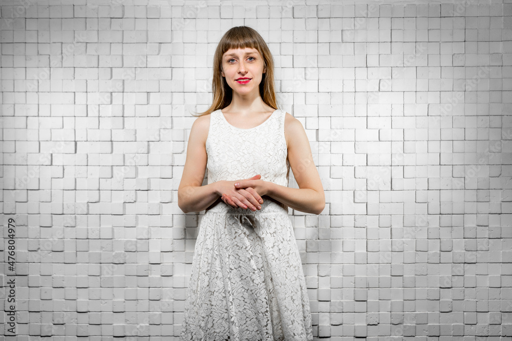 A pretty young lady in a white dress looks embarrassedly into the camera, smiling. Portrait of a girl with natural hair color, freckles A pretty young lady in a white dress looks embarrassedly into the camera, smiling. Portrait of a girl with natural hair color, freckles