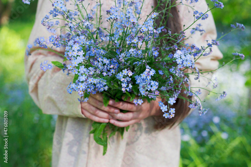 bouquet of blue forget me not flowers in girl hands in spring forest