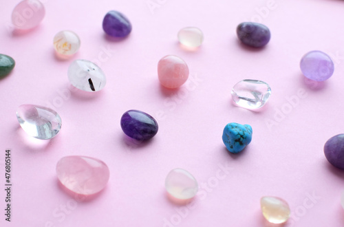 Gems of different colors. Amethyst, rose quartz, agate, apatite, aventurine, olivine, turquoise, aquamarine, rhinestone lie on a pink background. Flat lay
