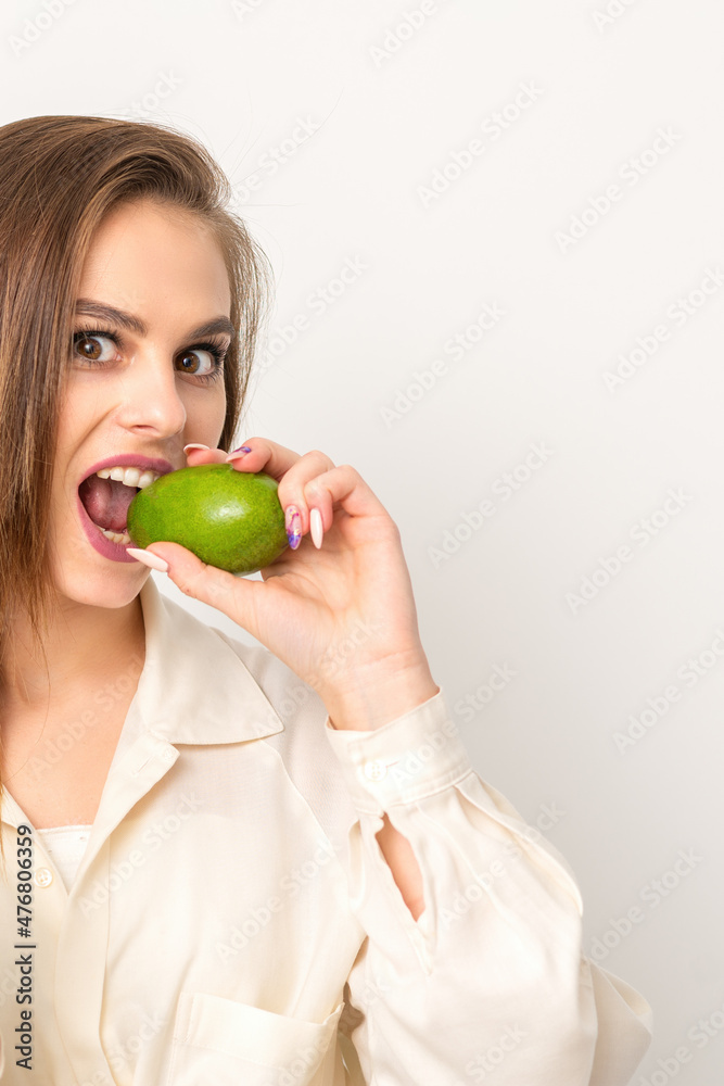 Diet nutrition. Beautiful young caucasian woman biting organic green avocado on white background. Healthy lifestyle, health concept Diet nutrition. Beautiful young caucasian woman biting organic green avocado on white background. Healthy lifestyle, health concept