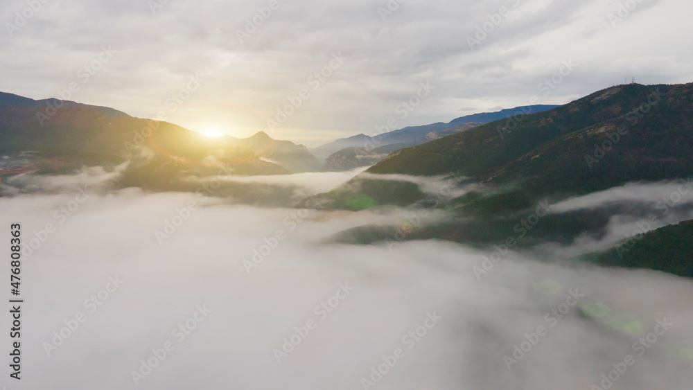 sunrise over mountains with many clouds, drone view