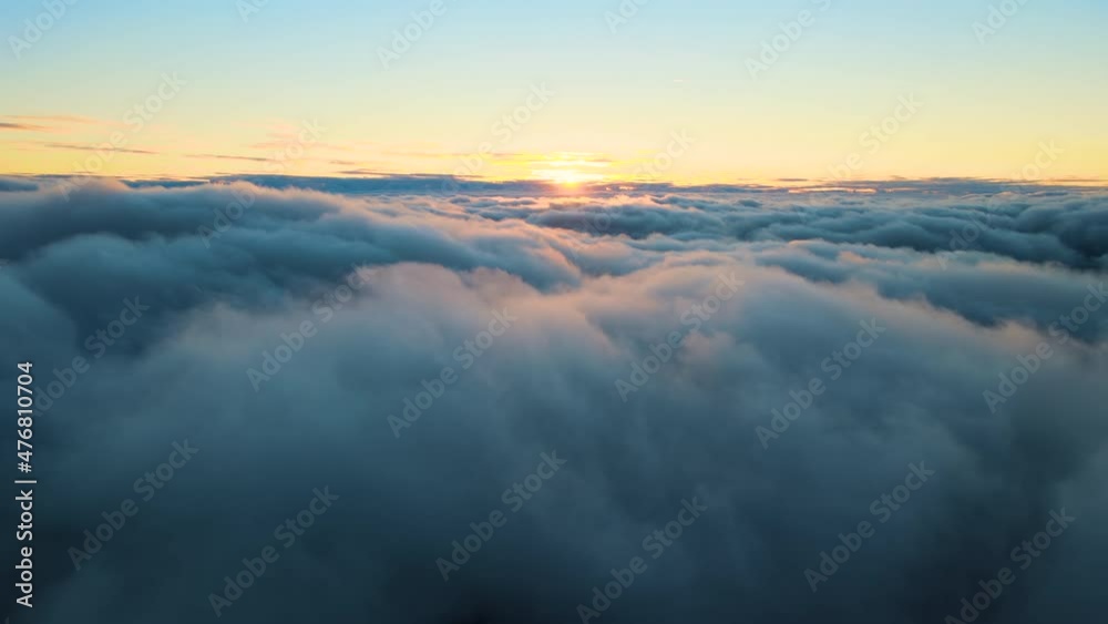 Aerial view from airplane window at high altitude of dense puffy cumulus clouds flying in evening Aerial view from airplane window at high altitude of dense puffy cumulus clouds flying in evening