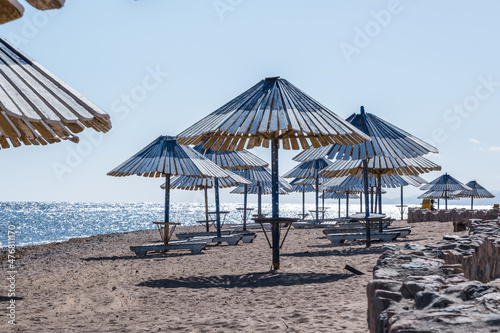Fototapeta Naklejka Na Ścianę i Meble -  wooden beach umbrellas and sun loungers by the red sea in bright sunny day