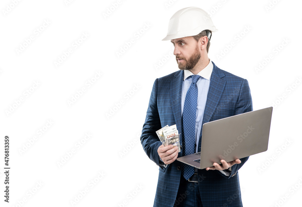 Professional man engineer in hardhat and suit hold money and laptop, working cost Professional man engineer in hardhat and suit hold money and laptop, working cost