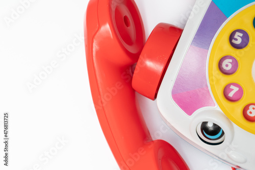 Children's toy landline phone with a red receiver, a dial and a smile on the body isolated on white photo