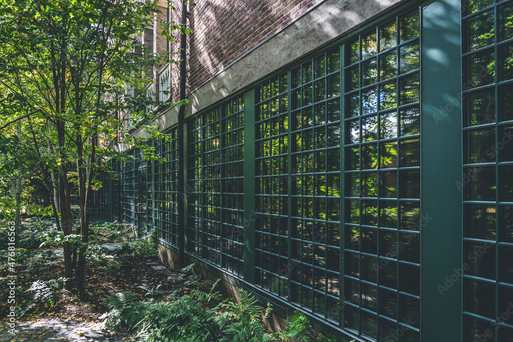 Fototapeta premium Brick wall with big glass windows secured with metal bars in the garden area