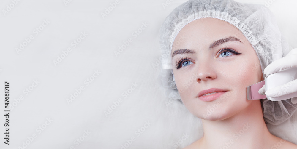 View from above of beautiful woman with smooth skin getting facial in modern beauty salon. Hands of beautician, in white gloves, doing ultrasonic cleaning with help of special apparatus. View from above of beautiful woman with smooth skin getting facial in modern beauty salon. Hands of beautician, in white gloves, doing ultrasonic cleaning with help of special apparatus.