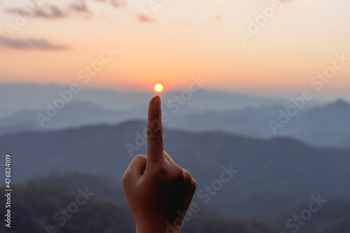 Silhouette female hands holding sun on mountain