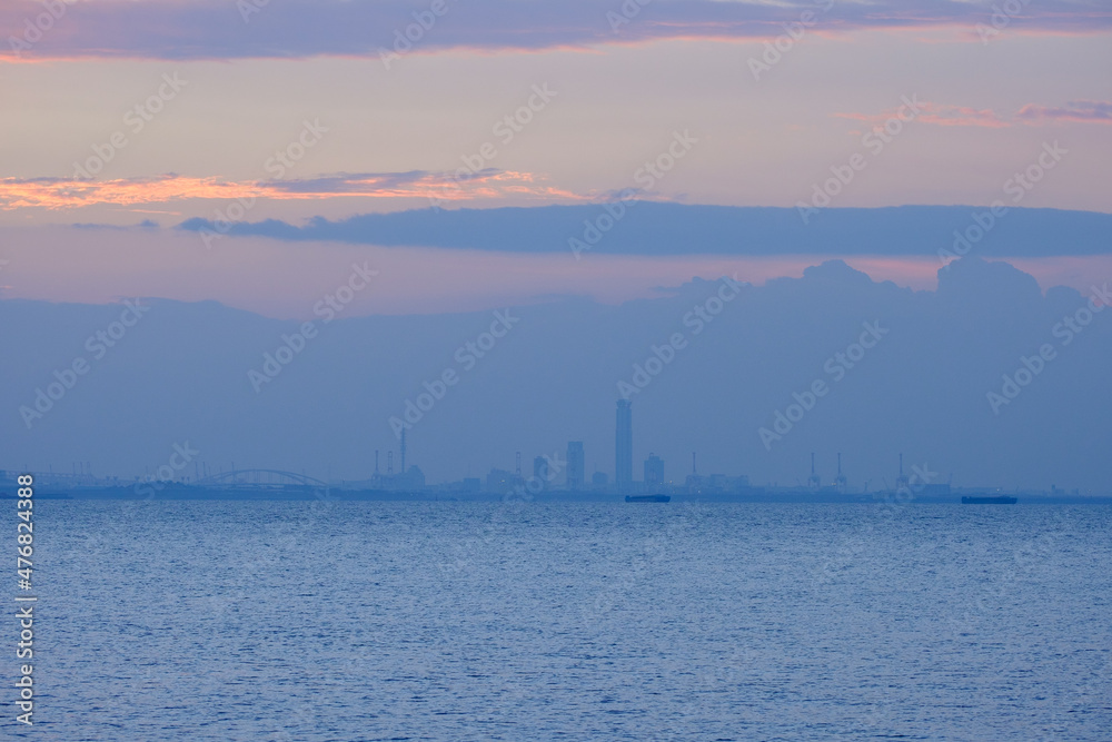 早朝、兵庫県芦屋市芦屋浜より大阪湾、西宮浜方面を臨む。空がオレンジ色に染まり大阪南港のビル群がシルエットで浮かぶ