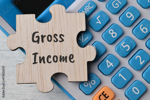 Fotografie Calculator and wooden puzzle with text GROSS INCOME