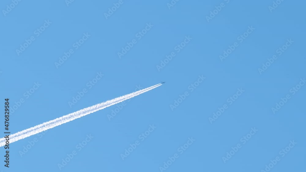 Distant passenger jet plane flying on high altitude on clear blue sky leaving white smoke trace of contrail behind. Air transportation concept Distant passenger jet plane flying on high altitude on clear blue sky leaving white smoke trace of contrail behind. Air transportation concept