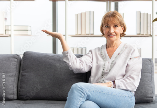 Free Download portrait senior woman smiling and raise arm showing pose on sofa - GFXLoad