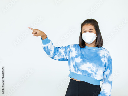 Portrait Asian woman wearing a face mask poses, pointing advertisement on white background, blank copy space with isolated cutout.