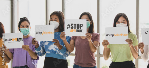 Group of multi races Asian women wearing protective hygiene face masks shake banners during participants in Asian American Pacific Islanders rally marching protest to stop hate on AAPI citizen. photo