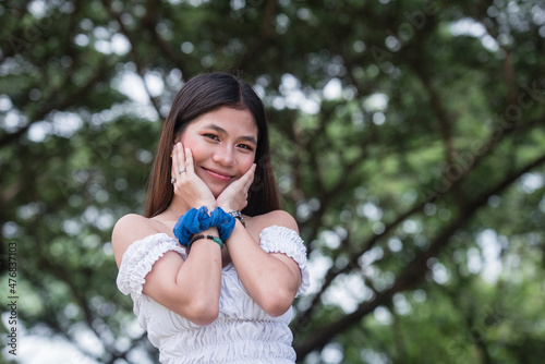 A cute and lovely young asian woman, with her hands on her cheeks. Outside park scene. photo